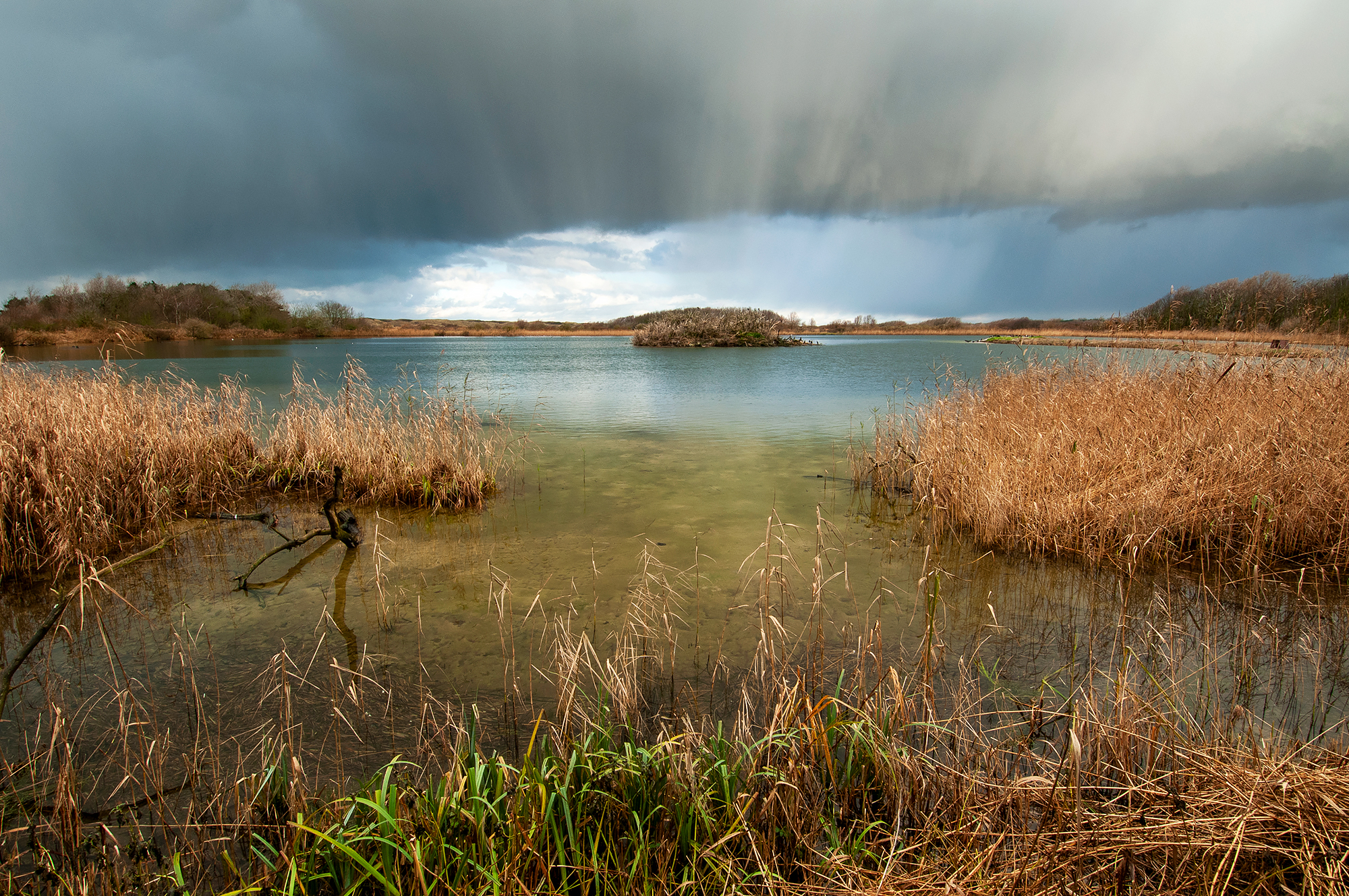 Wolken van regenbui boven het hoefijzermeer in het infiltratiegebied van het Noordhollands Duinreservaat bij Castricum