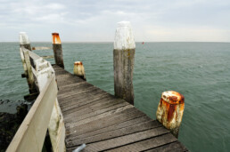 Verweerde, houten steiger tijdens onstuimige, bewolkte dag in de haven van het Waddeneiland Vlieland.