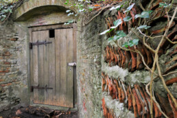 Een met dakpannen beklede muur leidt naar ingang van de ijskelder op het Landgoed Elswout in Overveen.