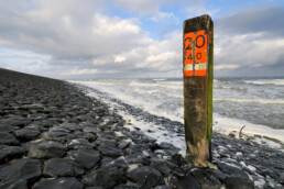 Zwarte keien en houten paal op de dijk van de Hondsbossche Zeewering bij Petten