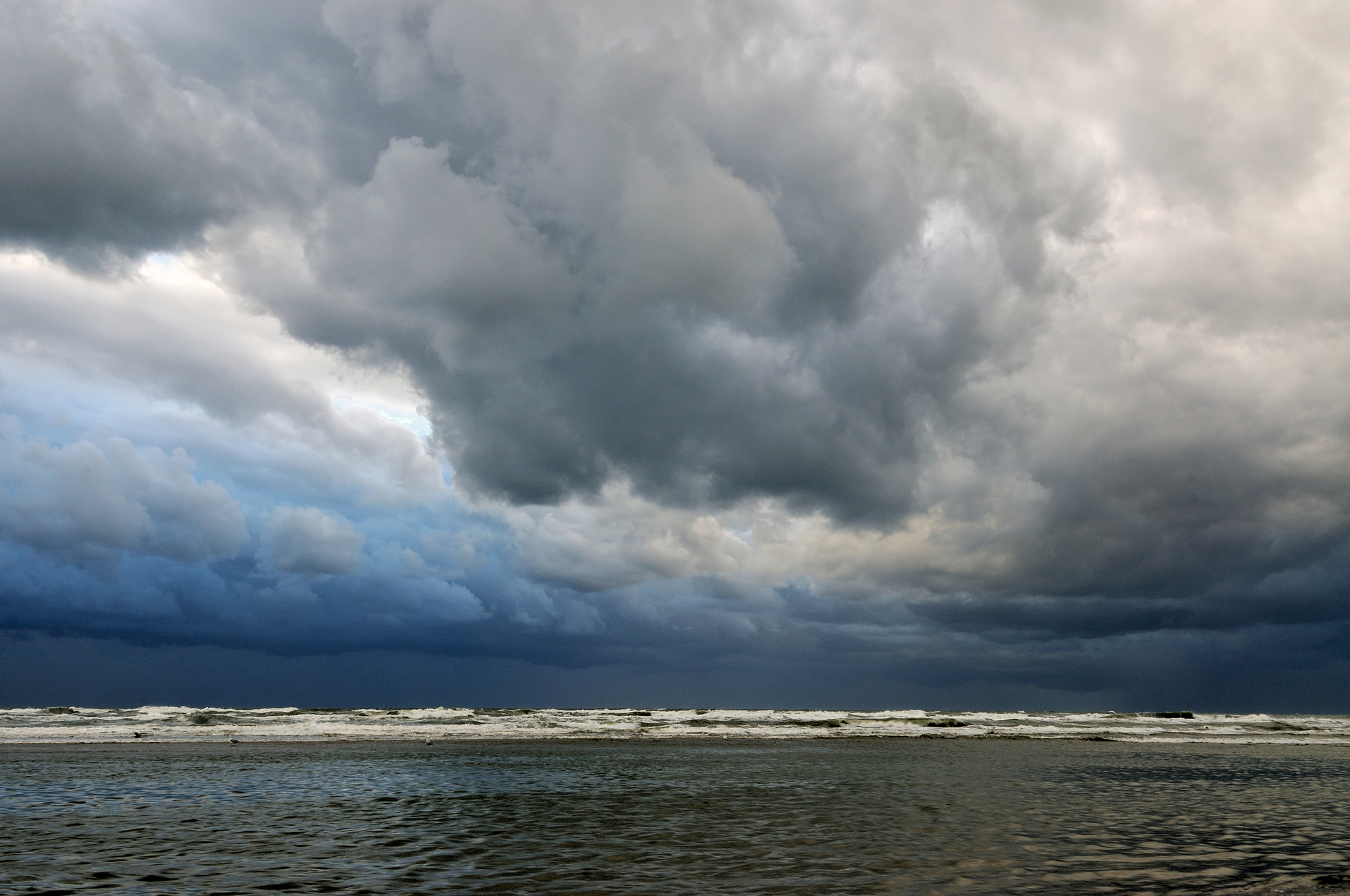 Donkere, dreigende wolkenlucht tijdens storm boven zee op het strand van Wijk aan Zee.