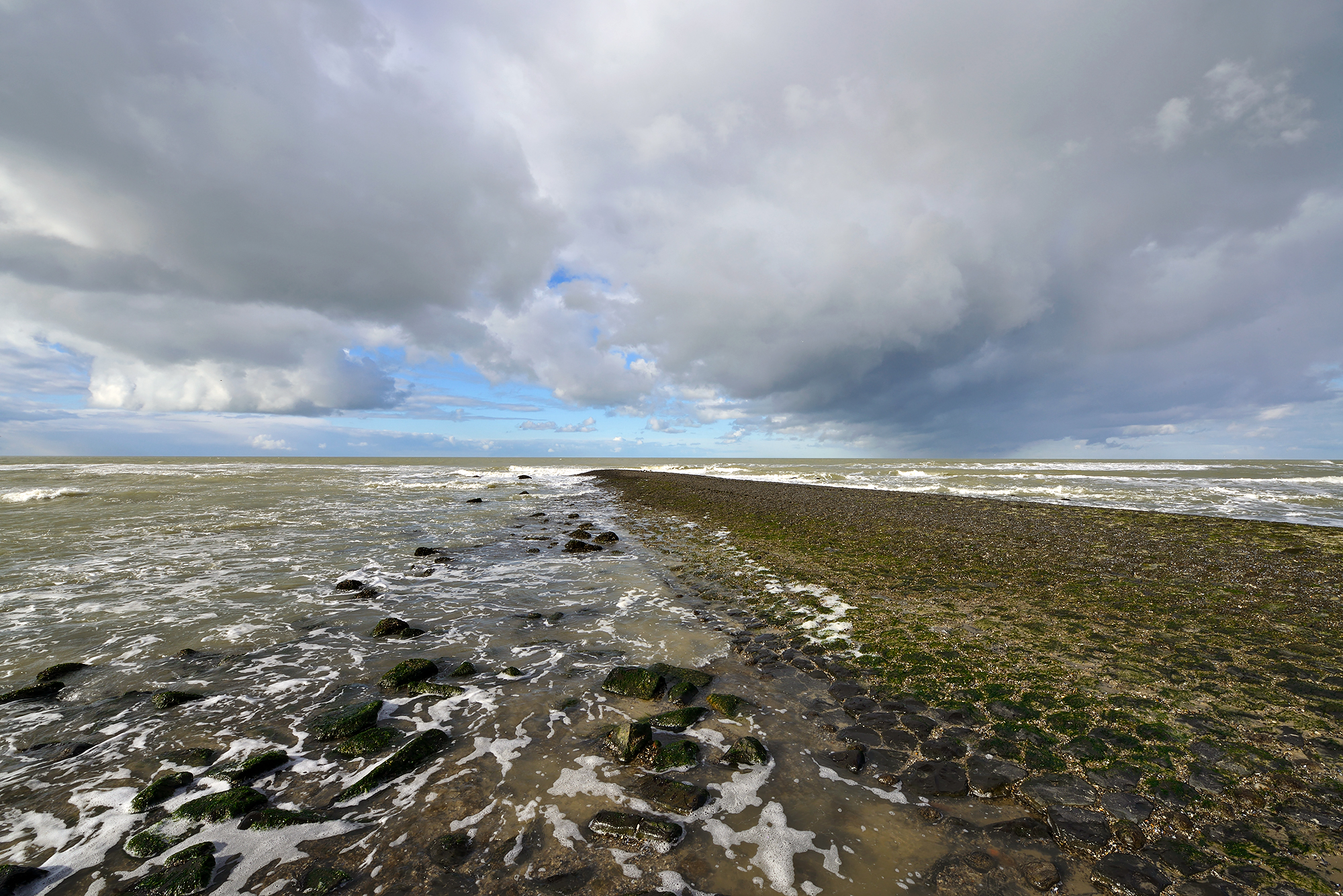 Dreigende wolken van naderende storm boven de noordzee en strekdam van de Hondsboscche Zeewering bij Petten