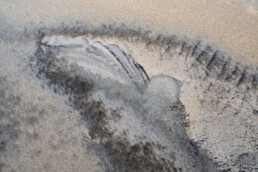 Wind en water hebben vormen in het zand gecreëerd die op een walvis lijken op het strand van Heemskerk.
