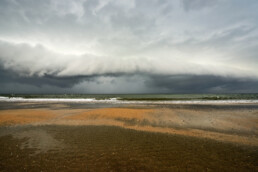 Grote, dreigende rolwolk nadert het land vanuit zee tijdens storm op het strand van Heemskerk.