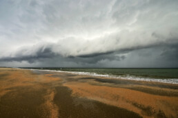 Grote, dreigende rolwolk nadert het land vanuit zee tijdens storm op het strand van Heemskerk.