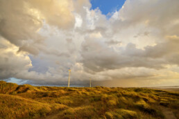 Wolkenlucht boven de zeeduinen en windmolens tijdens storm op het strand van Wijk aan Zee