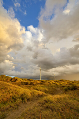 Wolkenlucht boven de zeeduinen en windmolens tijdens storm op het strand van Wijk aan Zee
