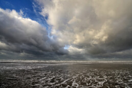 Grote wolkenluchten worden door de wind over de zee geblazen tijdens storm op het strand van Wijk aan Zee