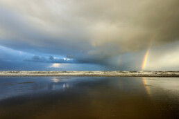 Een regenboog aan de onderkant van een hagelbui boven de Noordzee op het Kennemerstrand bij IJmuiden.