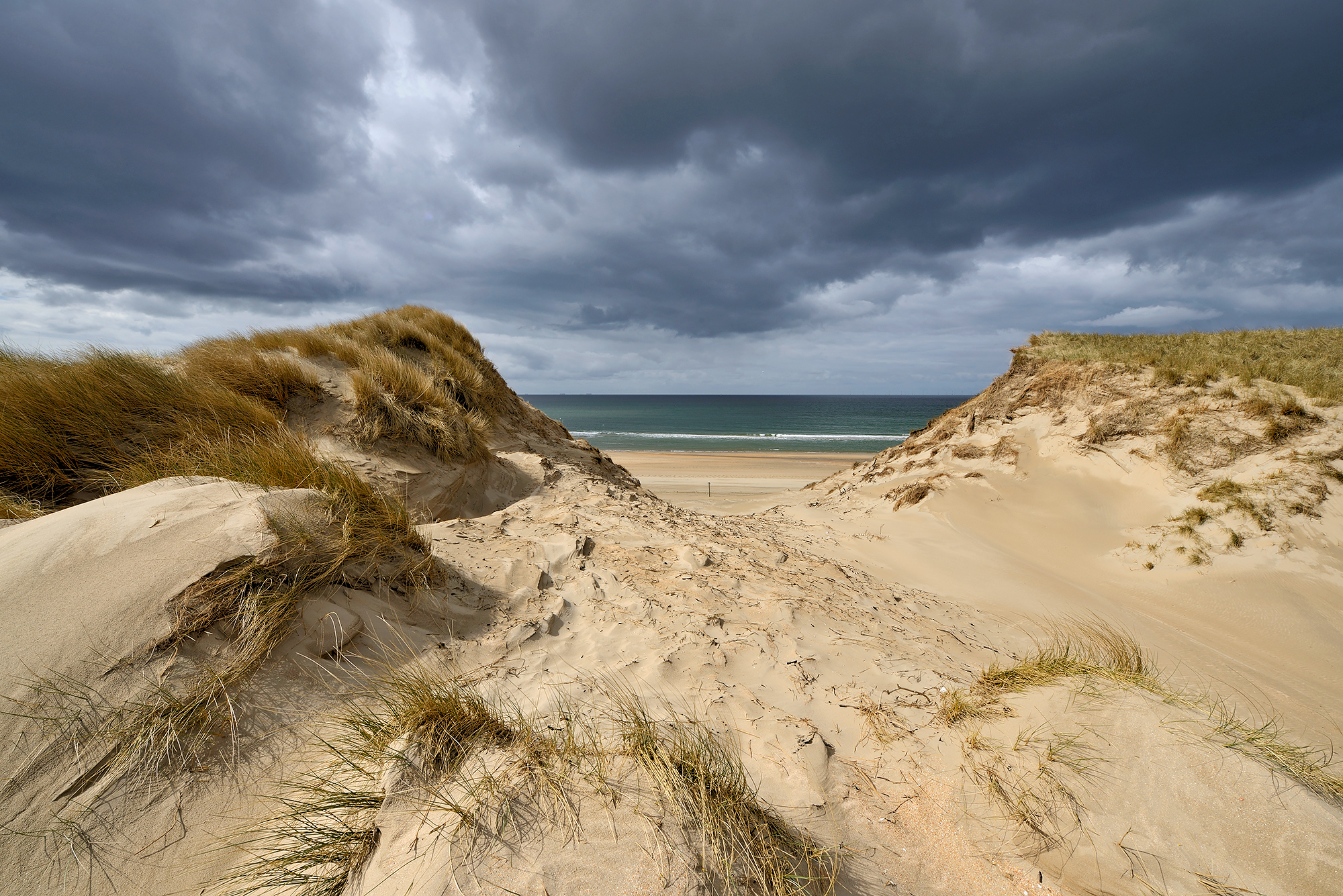 Donkere wolken boven een grote kerf in de zeeduinen van het Noordhollands Duinreservaat op het strand van Heemskerk.