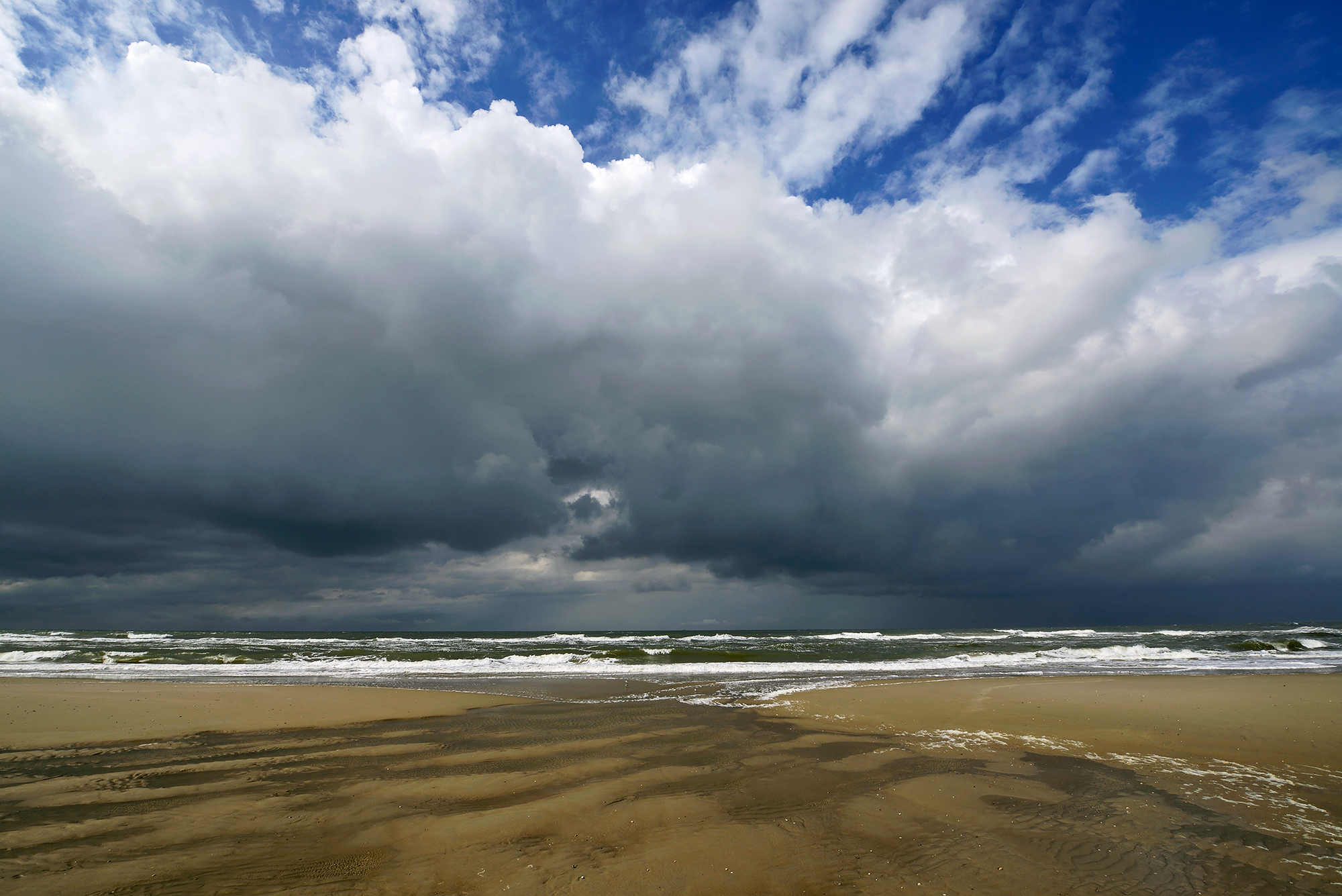 Grote, donkere wolkenlucht van naderende bui boven de Noordzee op het strand van het Waddeneiland Texel.