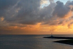 Uitzicht vanaf de veerboot naar Texel op warm licht van zonsopkomst op grote wolkenlucht van bui boven de Waddenzee