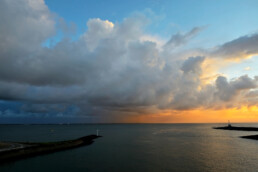 Uitzicht vanaf de veerboot naar Texel op warm licht van zonsopkomst op grote wolkenlucht van bui boven de Waddenzee