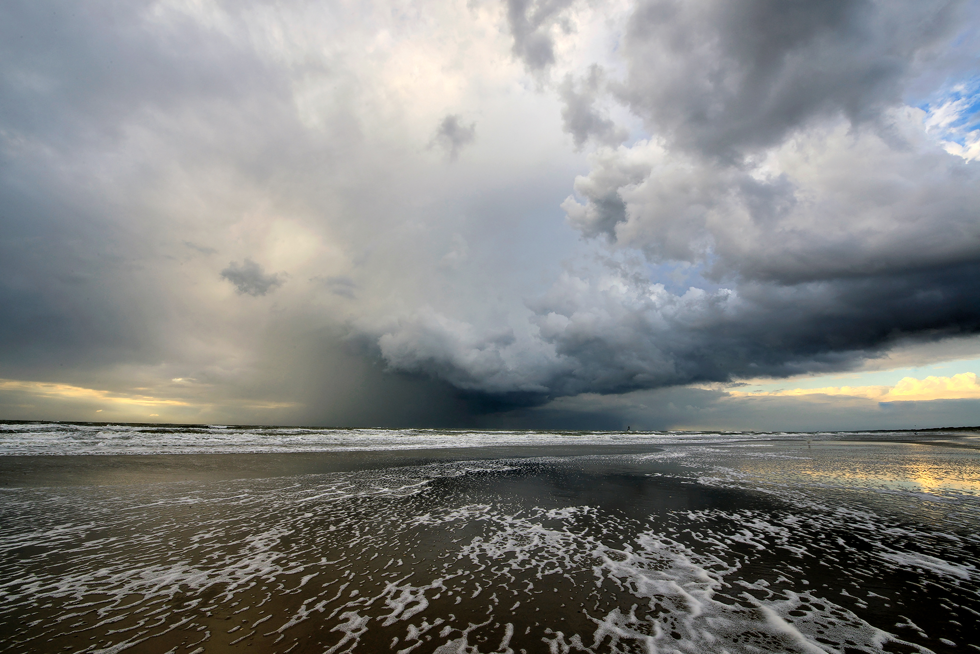 Donkere, dreigende wolkenlucht van naderende hagelbui boven zee tijdens storm op het strand van Wijk aan Zee