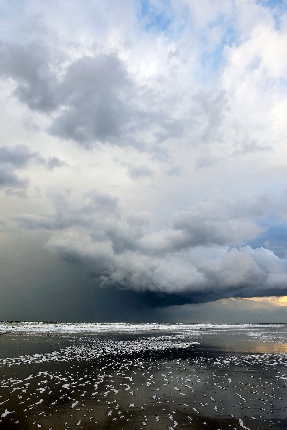 Donkere, dreigende wolkenlucht van naderende hagelbui boven zee tijdens storm op het strand van Wijk aan Zee