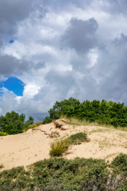 Wolkenlucht boven zanderige duinhelling van een stuifkuil in de Amsterdamse Waterleidingduinen bij Zandvoort.