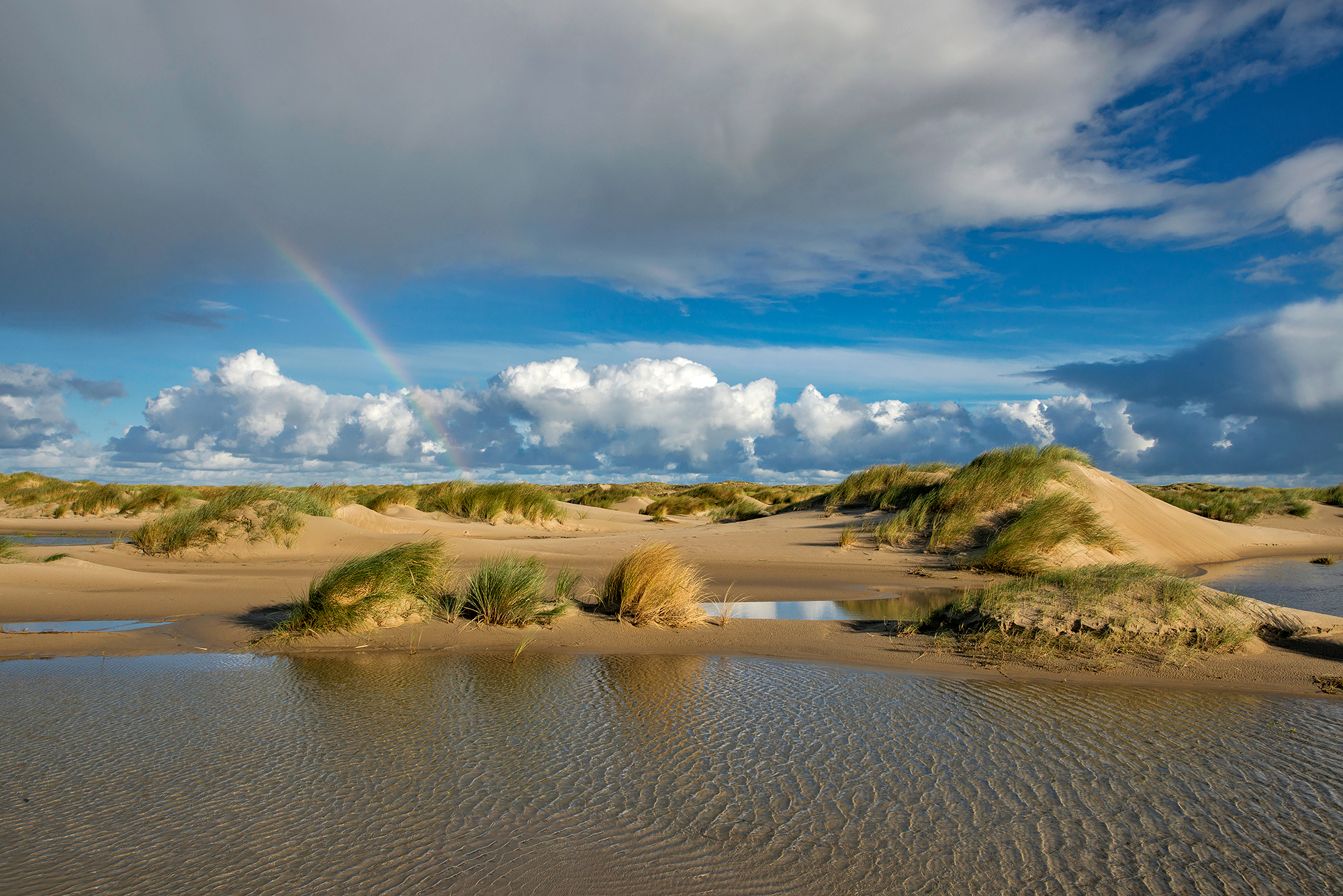Regenboog boven natte vallei tussen de zeeduinen op de strandvlakte van De Hors op de zuidpunt van Waddeneiland Texel.