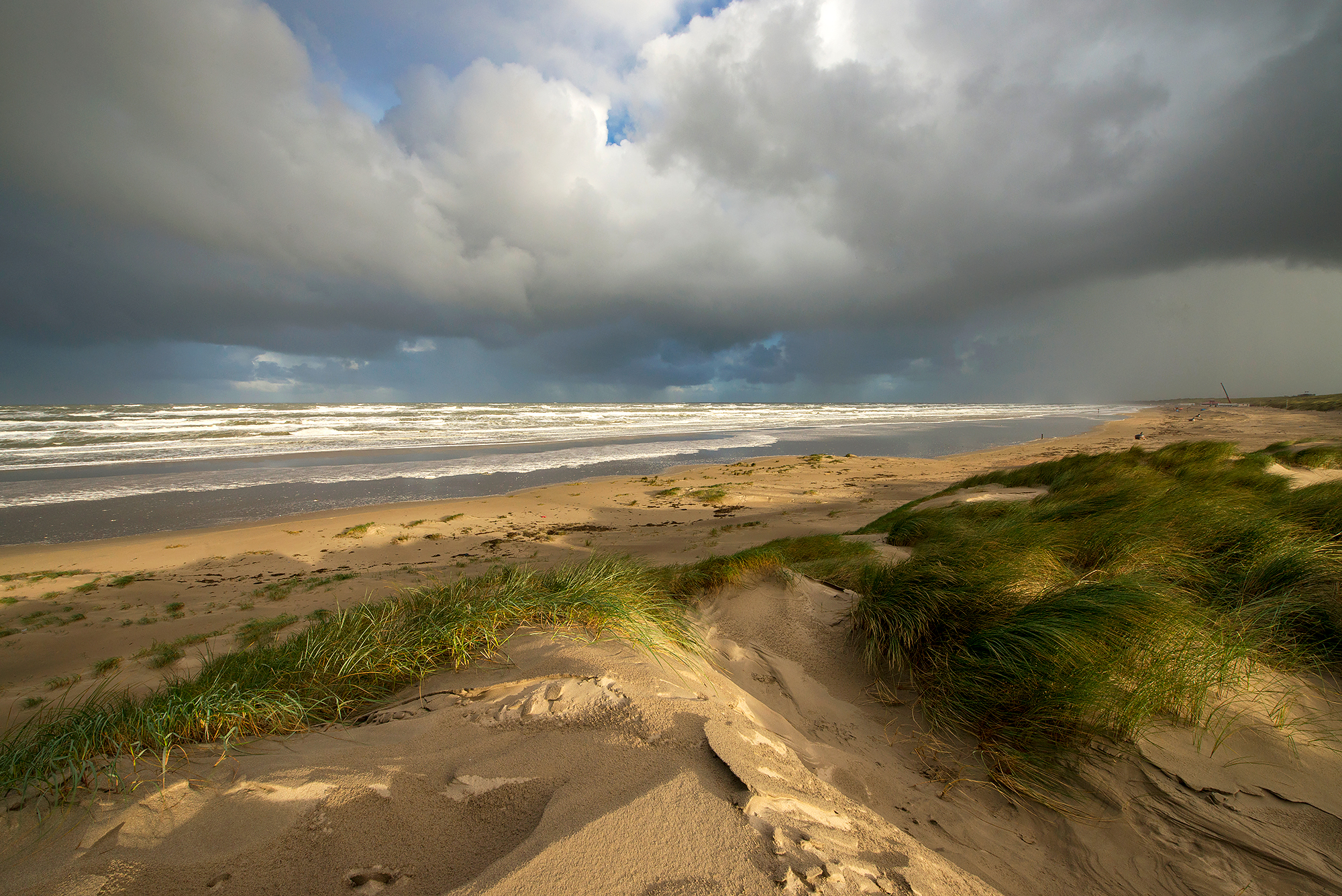 Harde wind en dreigende wolkenluchten boven zee tijds zonsopkomst op het strand van Wijk aan Zee