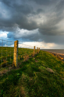 Donkere wolkenlucht van regenbui boven de dijk en Waddenzee bij het dorpje Vatrop op voormalig Waddeneiland Wieringen.