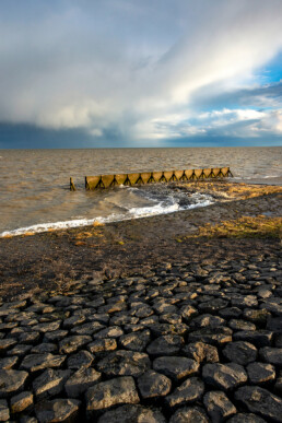 Uitzicht op dreigende wolkenlucht van naderende regenbui boven de Waddenzee vanaf de dijk bij Vatrop op Wieringen.