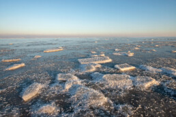 Stukken ijs op bevroren water van Waddenzee tijdens zonsopkomst op Wieringen