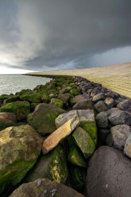 Donkere wolken van regenbui boven de waddenzeedijk van Oudeschild op het Waddeneiland Texel