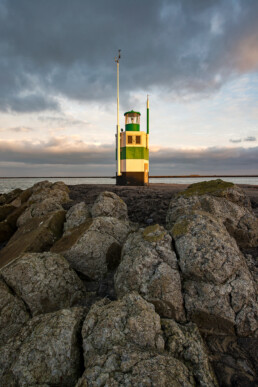 Warm licht van zonsopkomst schijnt op het lichthuis van de Zuidpier bij IJmuiden