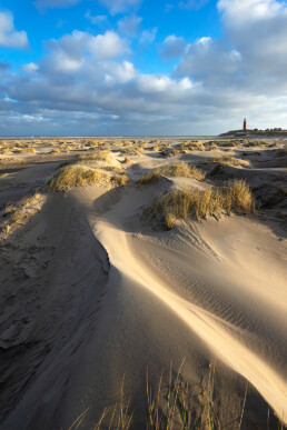 Zonlicht schijnt over duintjes op het strand bij de vuurtoren Eierland op het Waddeneiland Texel